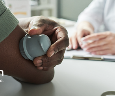 Person applying a continuous glucose monitor to their arm in front of a healthcare professional at their office