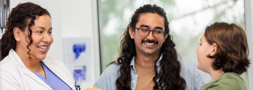 Female doctor speaking to dad and his daughter about continuous glucose monitors
